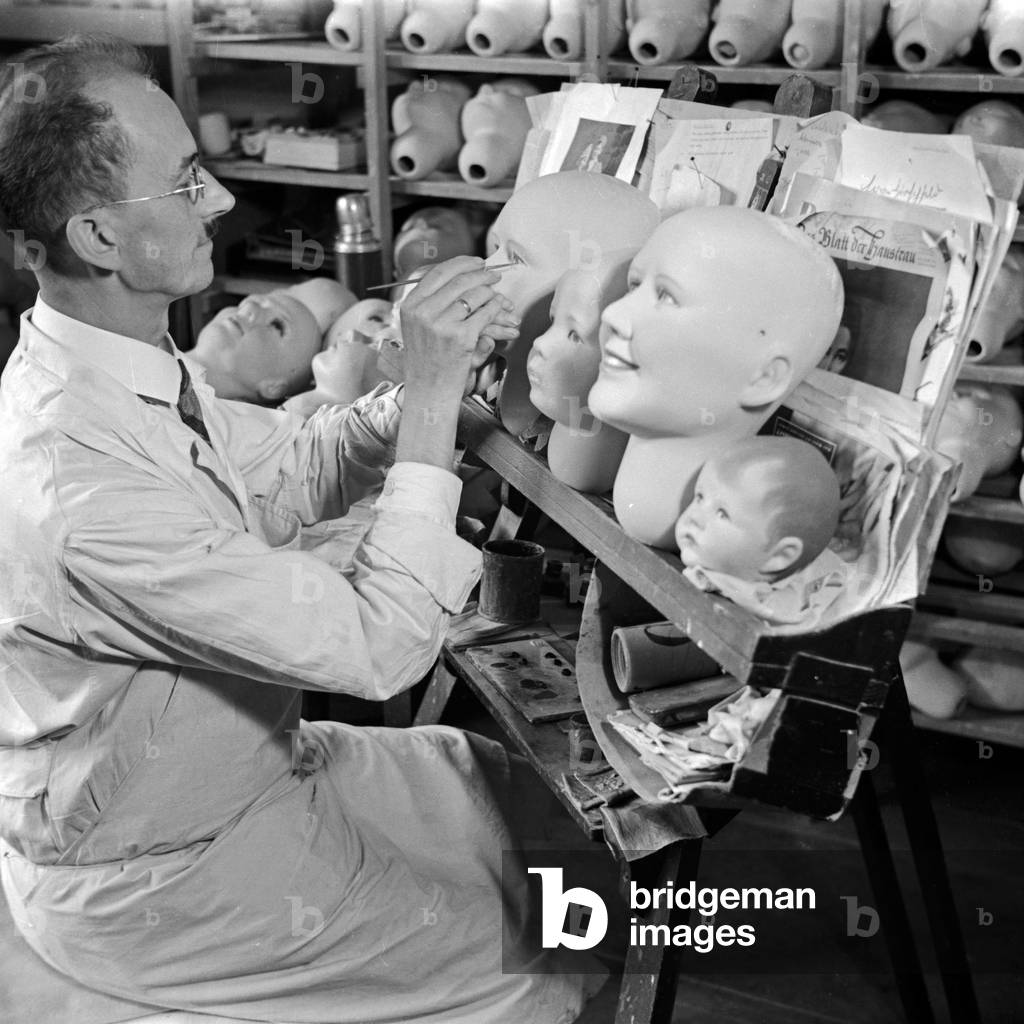 A modeller creating faces of the Kaethe Kruse display dummies, Germany 1930s (b/w photo)