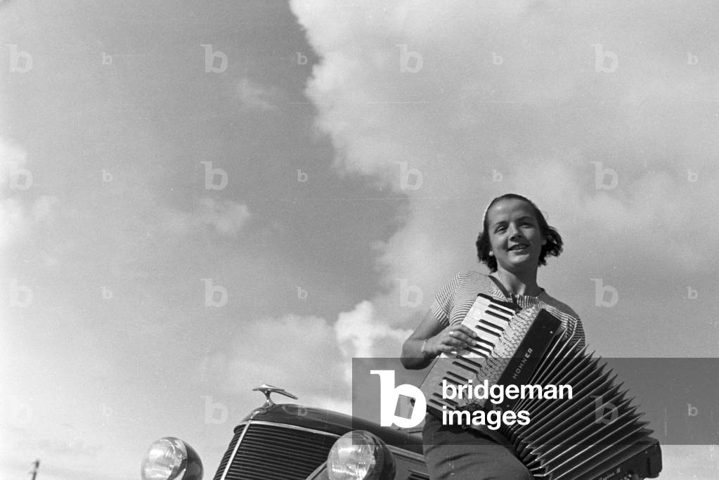 A young woman playing the harmonica, Germany 1930s (b/w photo)