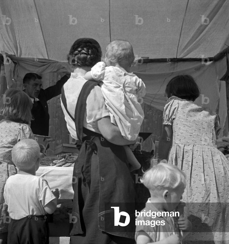 A group of people crwoding in front of a booth at a market, Deutschland 1930er Jahre (b/w photo)