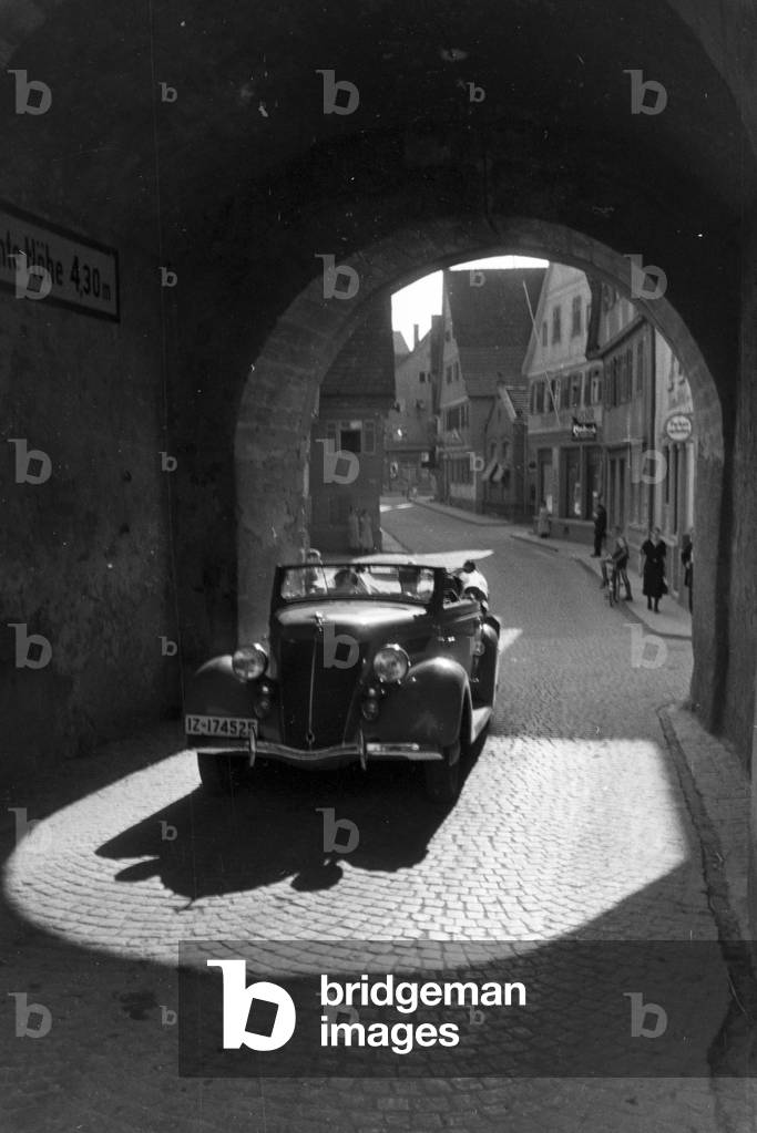Driving through the Beinsteiner Gate Tower in Waiblingen with a Ford V8, Germany 1930s (b/w photo)