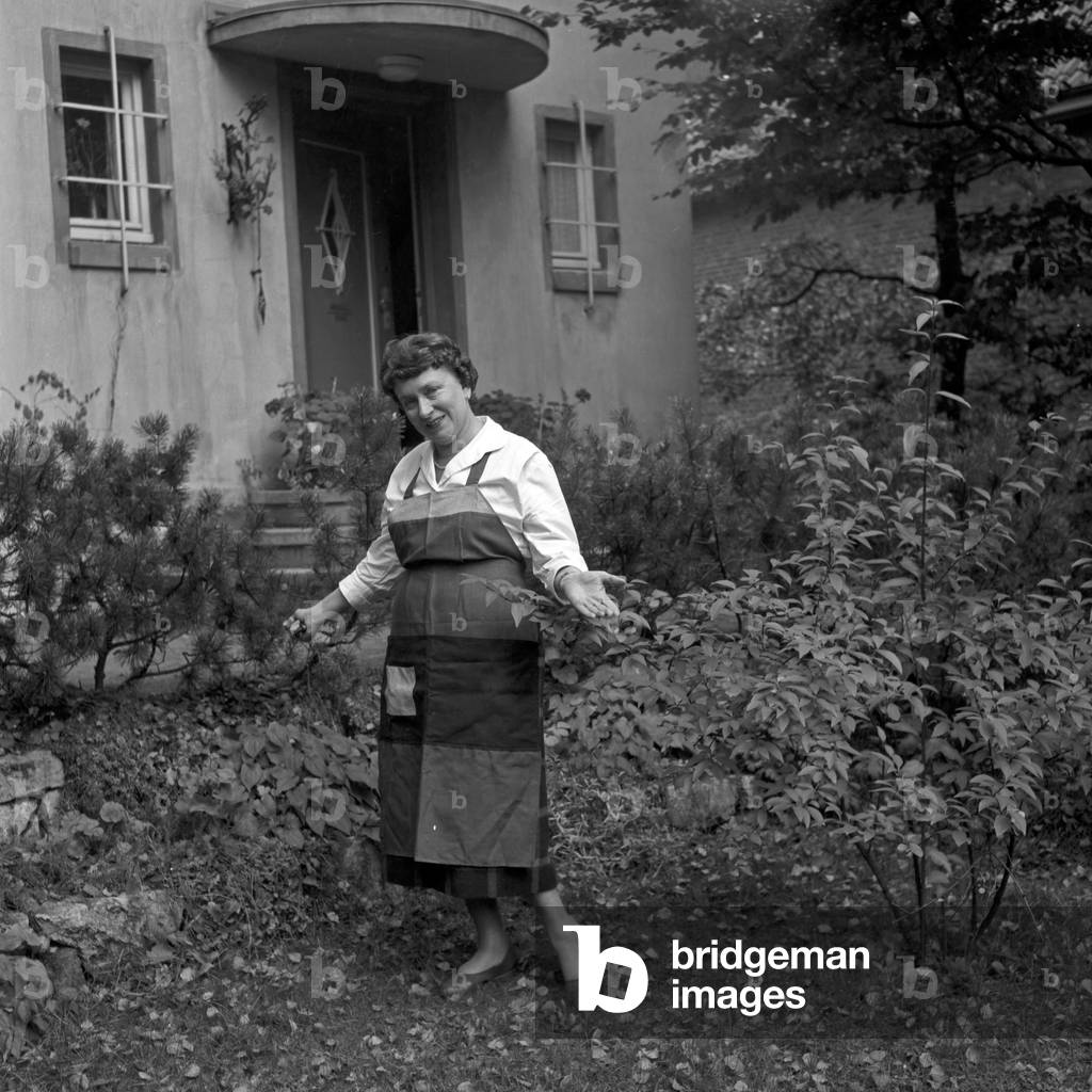 A housewife posing at the autumnal front garden of her house at Hamburg, Germany 1950s