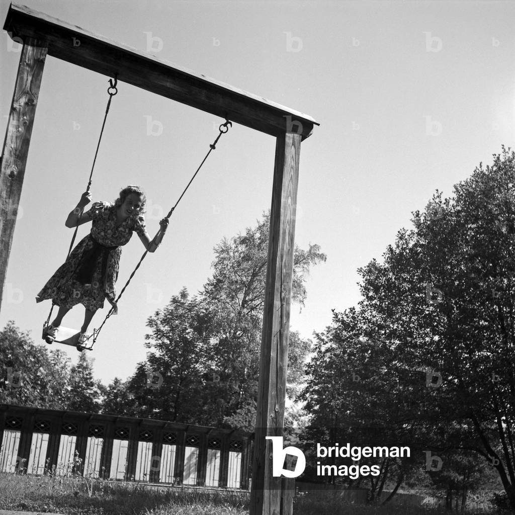 A young woman standing on a swing, Austria 1930s (b/w photo)