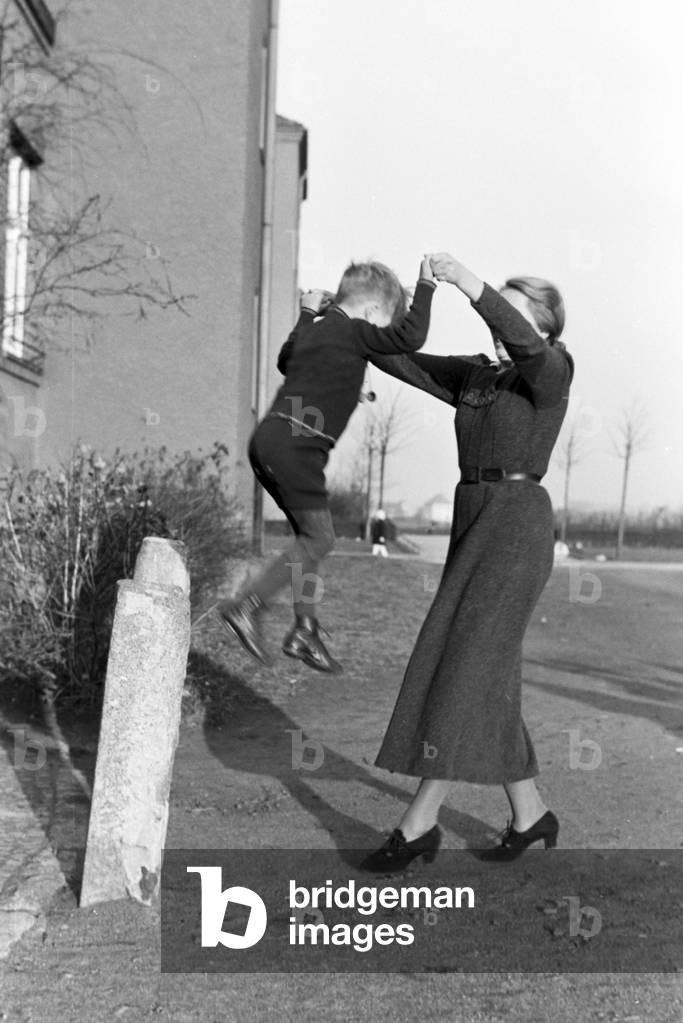 Members of a extended family playing in front of the apartment building , Germany 1930s (b/w photo)