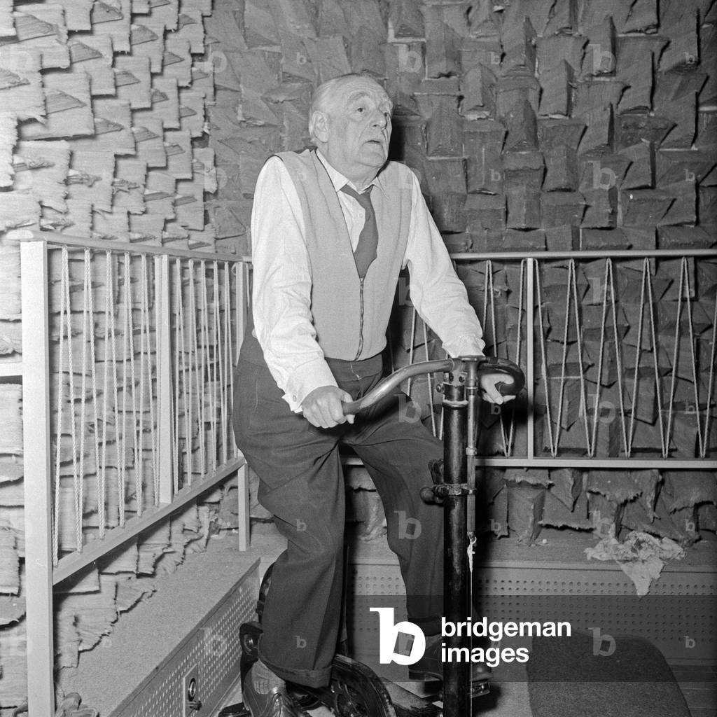 The sound of a bicycle is needed for the production of an audio play, so one of the speakers sits on a stationery bike in front of the microphone, Germany 1950s