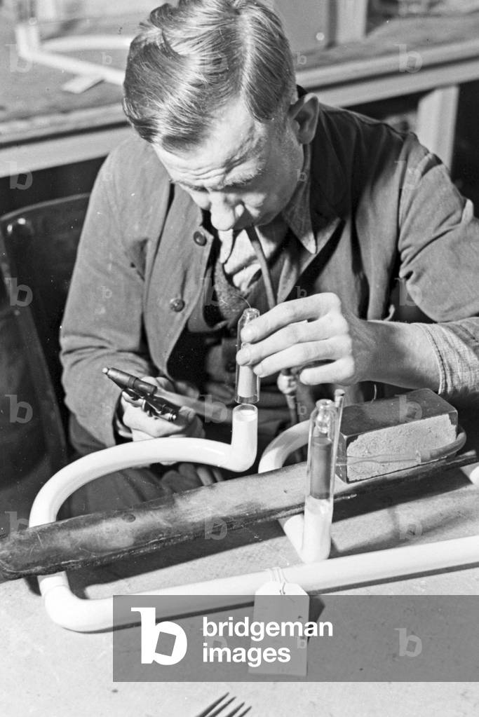 A staff member producing a fluorescent tube, Germany 1930s (b/w photo)