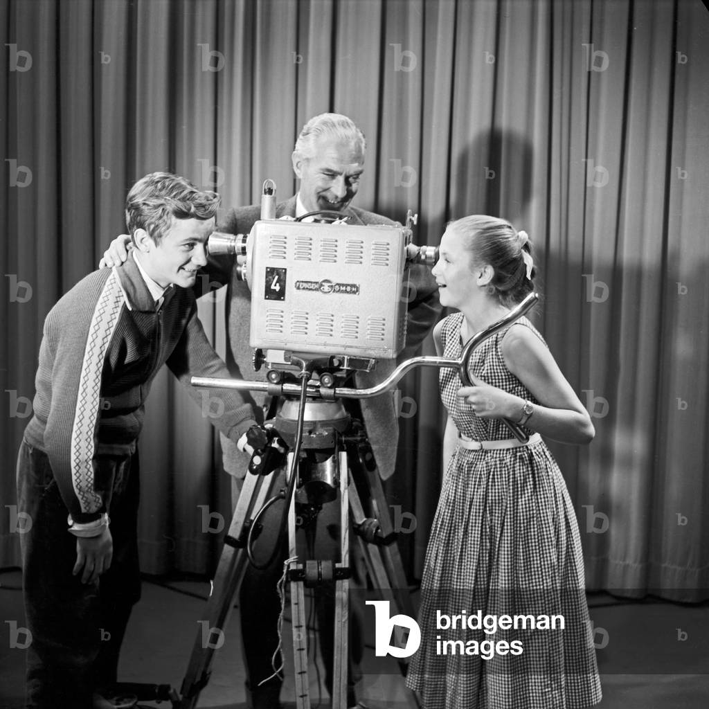 A camera man explaining how a TV camera work to a boy and a girl, Germany 1950s