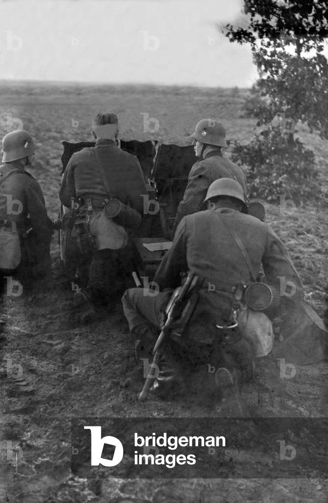 Infantry soldiers on a military training ground exercising with an infantry support gun, Germany 1930s (b/w photo)