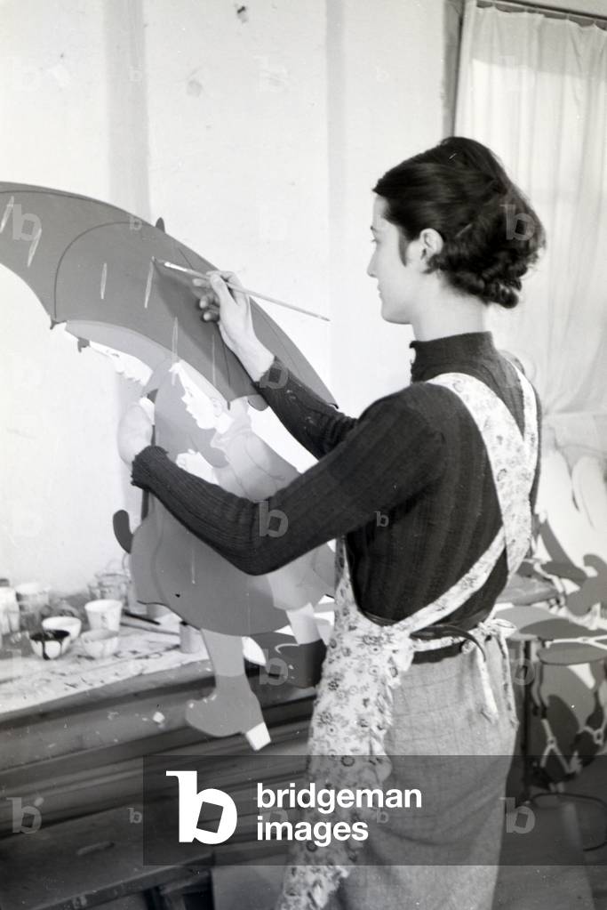 An employee of the Heller Kunst workshops in the Eifel painting a sawn out wooden figure, Germany 1930s (b/w photo)