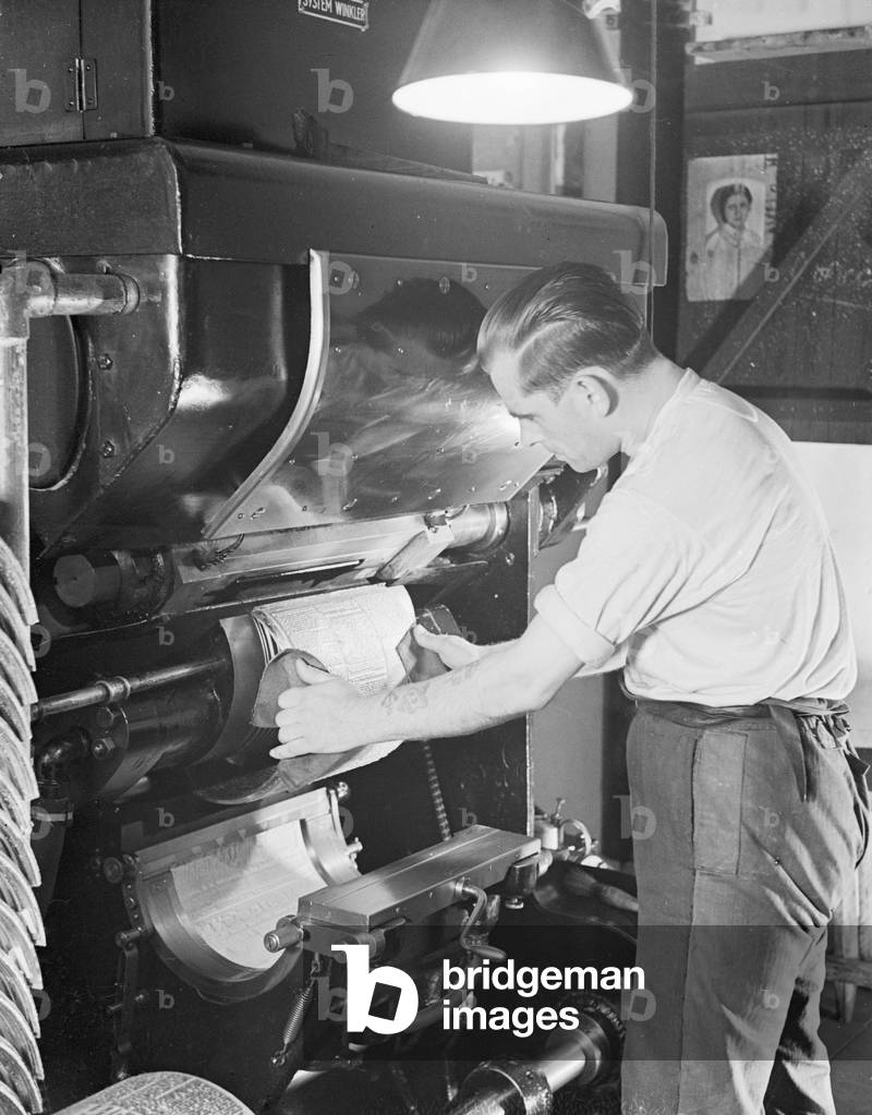 A man inserting a first print into a printing machine, Germany 1930s (b/w photo)