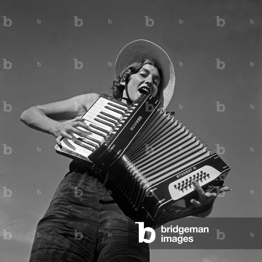 A young woman playing an accordion, Austria, 1930s (b/w photo)