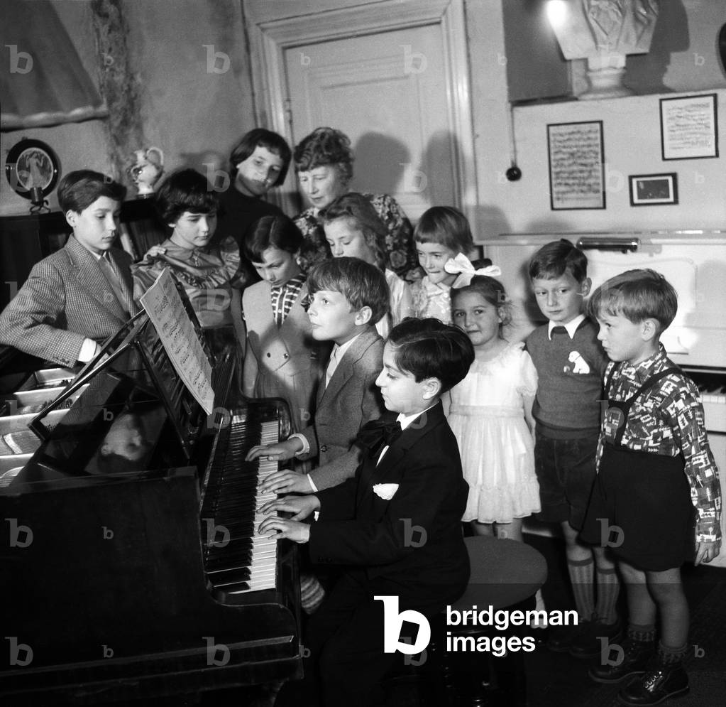 Children learn to play piano with their teacher