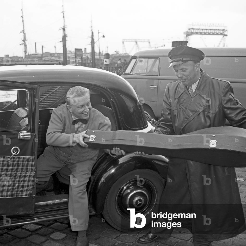 A taxi driver helping lutenist Richard Germer to enter the taxi at Hamburg, Germany 1950s