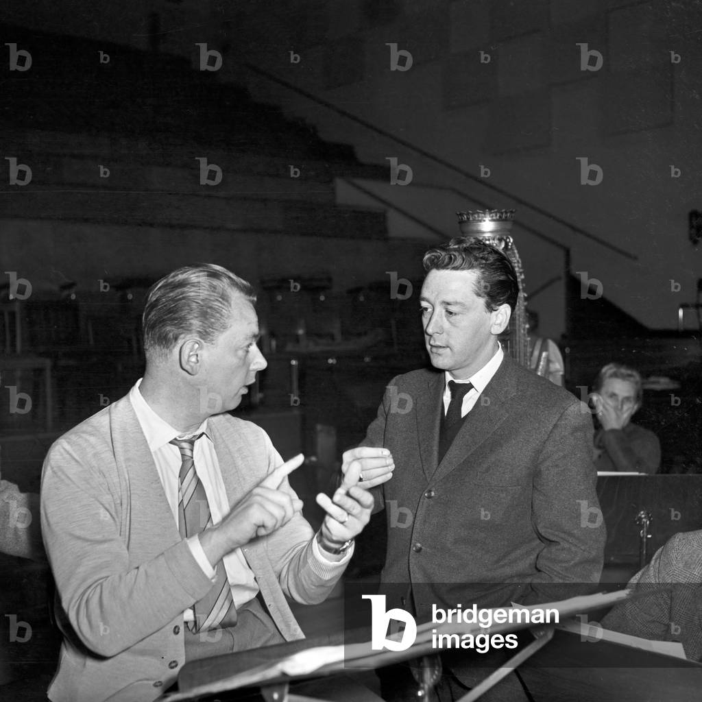 Irish singer Johnny Dane talking about musical arrangements with an orchestra conductor at Hamburg, Germany 1950s