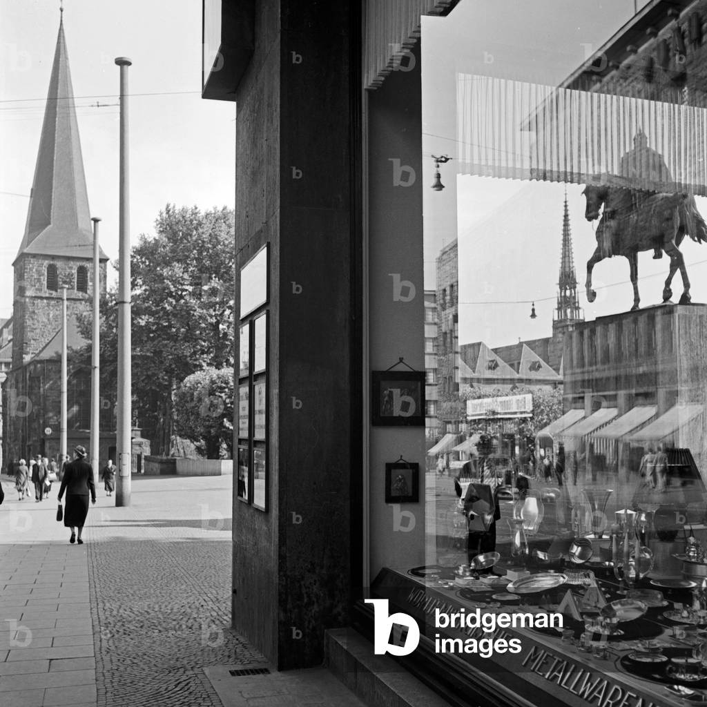 reflected in the showcase of a household goods store on Burgplatz in Essen, Germany 1930s (b/w photo)