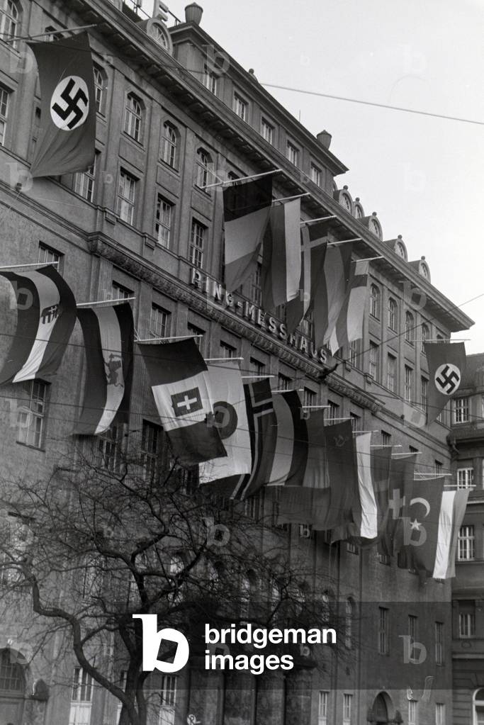 Exterior view of the Ring-Messehaus with flags of the participating nations of the Leipziger Frühjahrsmesse, Germany 1941 (b/w photo)