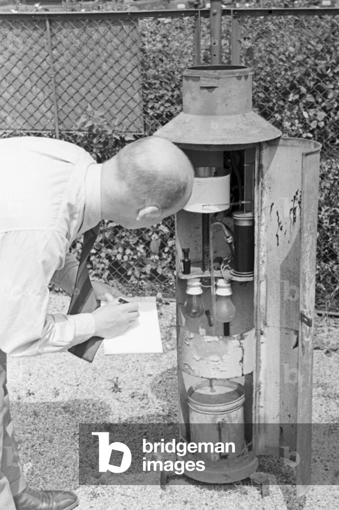 Staff member of a meteorological office measuring the rainfall, Germany 1930s (b/w photo)