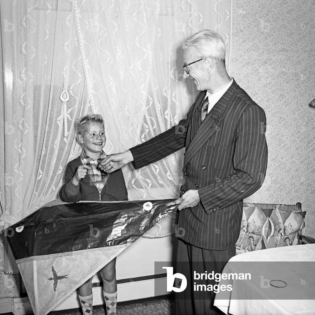 An elder man giving a kite to a little boy, Germany 1950s