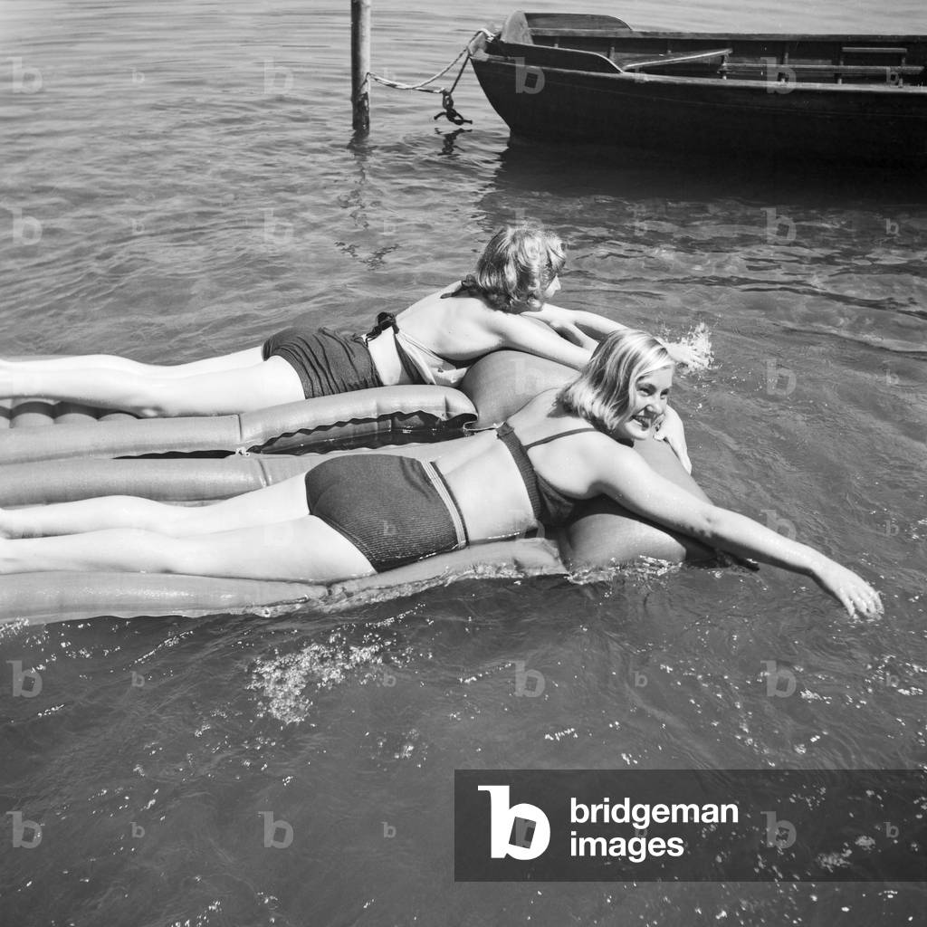 Two young women on an air matress on a lake in the Wachau area in Austria, Germany 1930s (b/w photo)