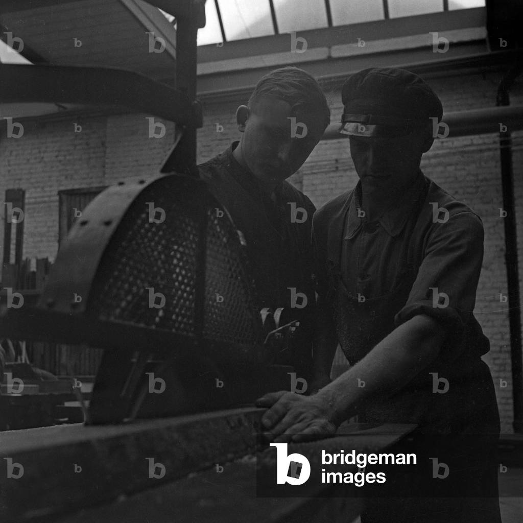 The safety engineer is interviewing a worker at a saw of a roll thread factory, Germany 1930s (b/w photo)