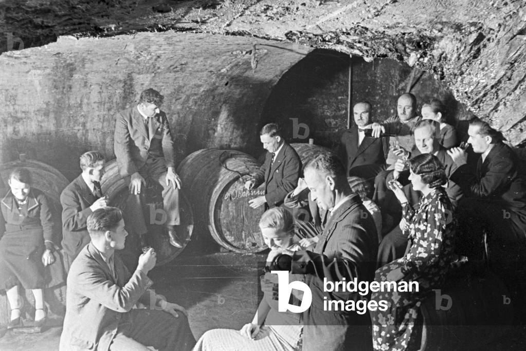 Guests checking the new vintage at the wine cellar, Germany 1930s (b/w photo)