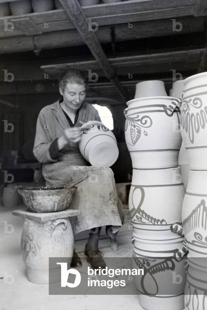 A master potter painting stoneware jars in the characteristic blue colour of the Westerwälder Stoneware, Germany 1930s (b/w photo)