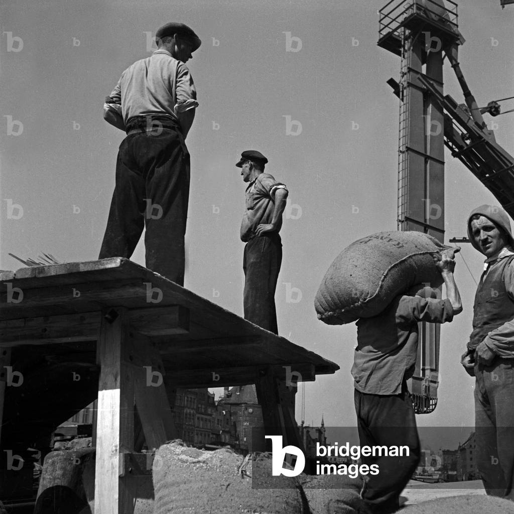 Harbor workers loading sacks into a cargo ship at Danzig harbor, Germany 1930s (b/w photo)