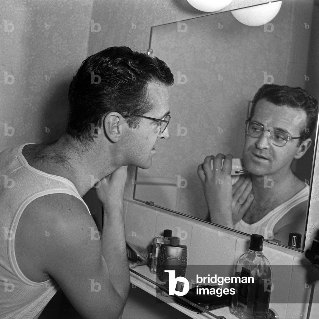 Swiss musician, singer and bandleader Hazy Osterwald shaving at his bathroom, Germany 1950s