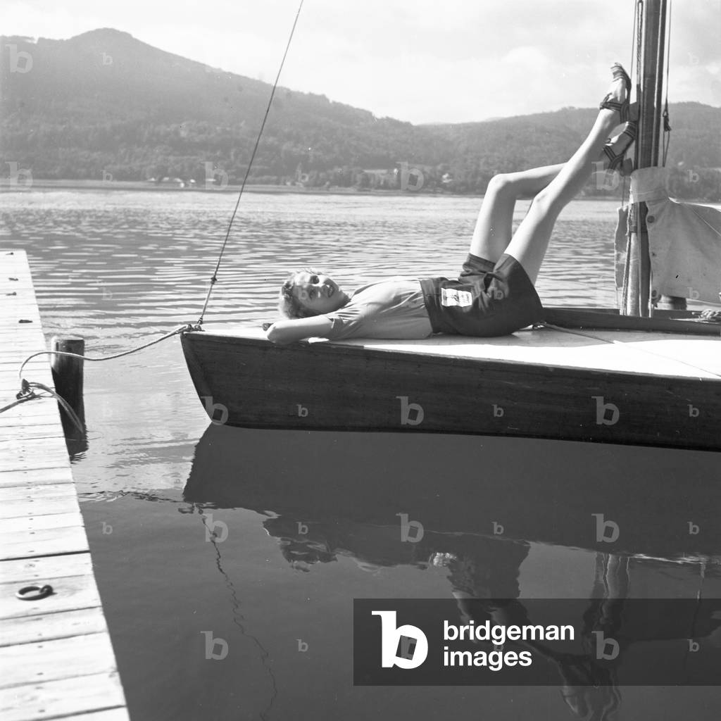 A young woman on a boat on the shore of a lake in the Wachau area, Germany 1930s (b/w photo)