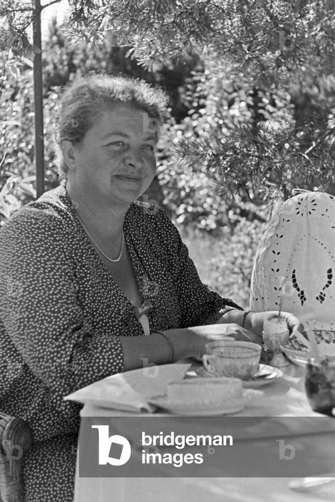 A woman sitting on the coffee table in her vacations at the Baltic Sea, Germany 1930s (b/w photo)