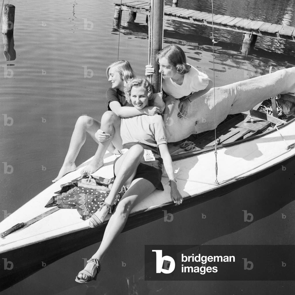Three young women on a sailing boat on a lake in the Wachau area in Austria, Germany 1930s (b/w photo)