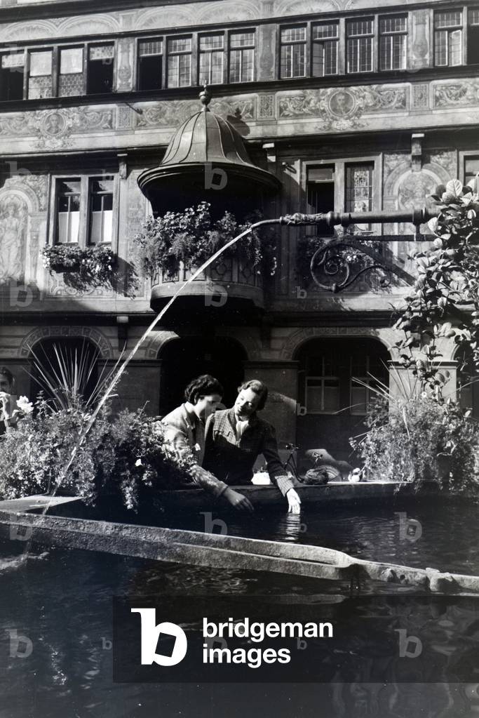 Besides the townhall, the fountain decorated with flowers is another object of interest at the market square in Tübingen, Germany 1930s (b/w photo)