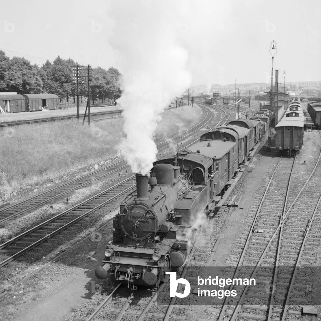 A freight train with a steam locomotive of type 31, leaving a little station, Germany 1930s (b/w photo)