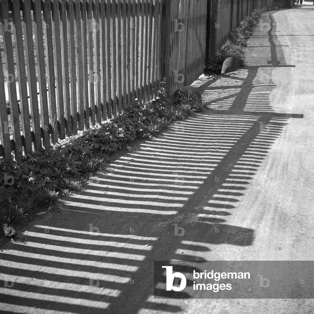 Light and shadow from a fence on a village path, Germany 1930s (b/w photo)