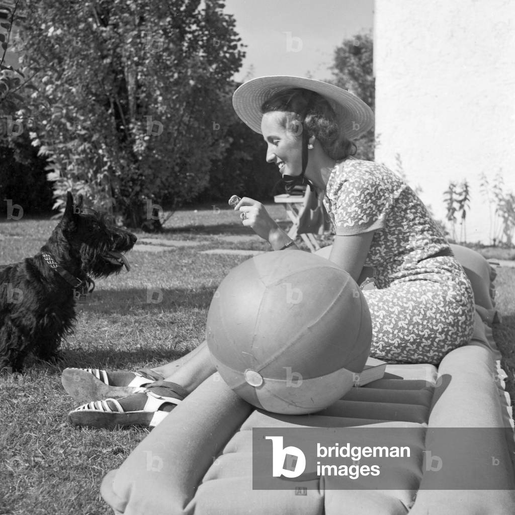 A young woman with her dog on a lawn, Germany 1930s (b/w photo)