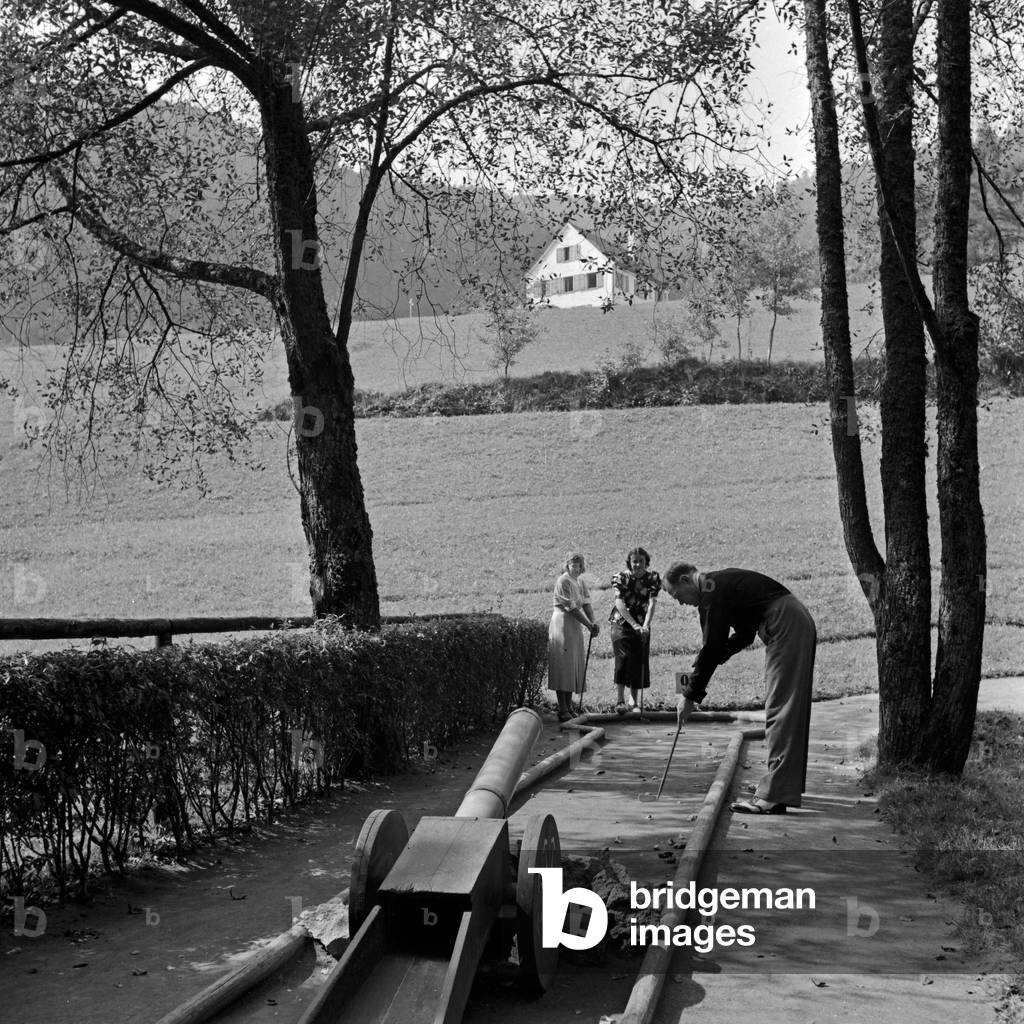 Twi women and a man playing crazy golf, Germany 1930s (b/w photo)