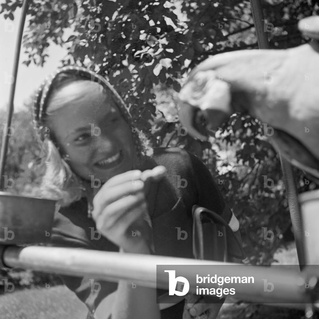 A young woman with a parrot at Wilhelma zoological garden in Stuttgart, Germany 1930s (b/w photo)
