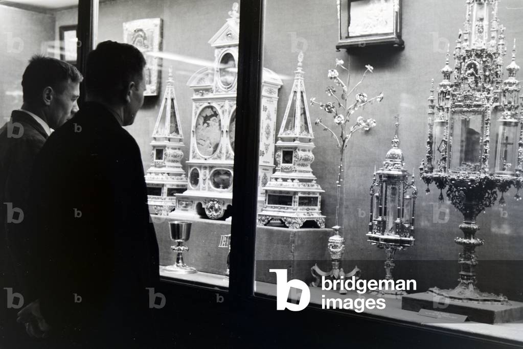 Visiors looking at a vitrine with exhibitions pieces in the Treasury of Munich Residenz, Germany 1930s (b/w photo)