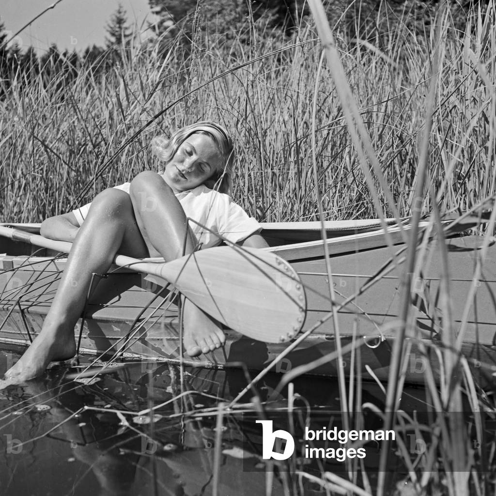 A young woman with her folding boat in the reed of a lake in the Wachau area, Germany 1930s (b/w photo)