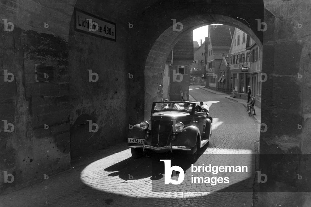 Driving through the Beinsteiner Gate Tower in Waiblingen with a Ford V8, Germany 1930s (b/w photo)
