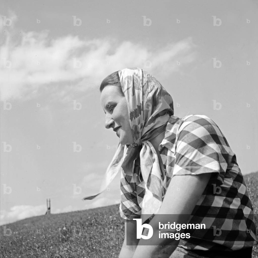 A young woman with a headscarf sitting in a lawn, Germany 1930s (b/w photo)