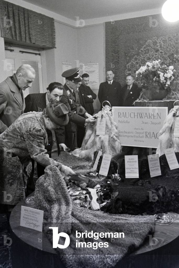 Visitors of the Leipziger Frühjahrsmesse in front of a stand with furs (coats) from the Iran, Germany 1941 (b/w photo)