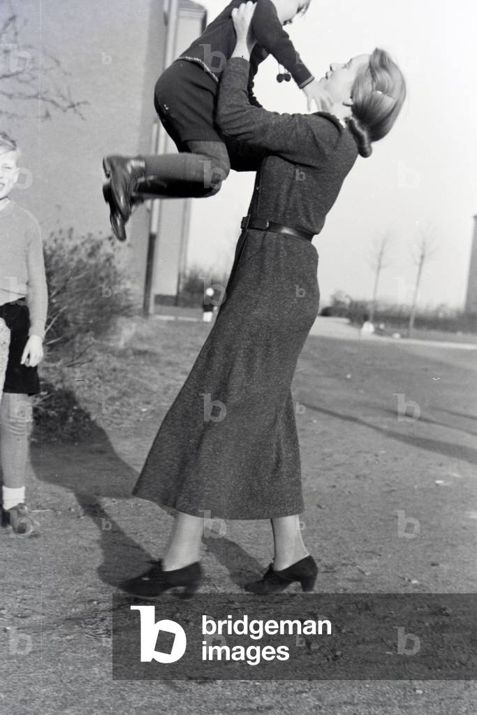 Members of an extended family playing in front of the apartment building , Germany 1930s (b/w photo)