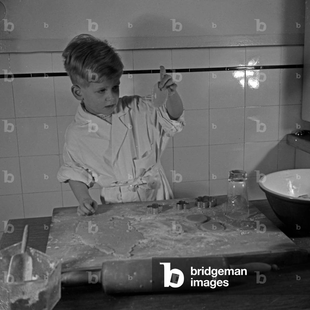 A little boy shaping dough for christmas cookies, Germany 1930s (b/w photo)
