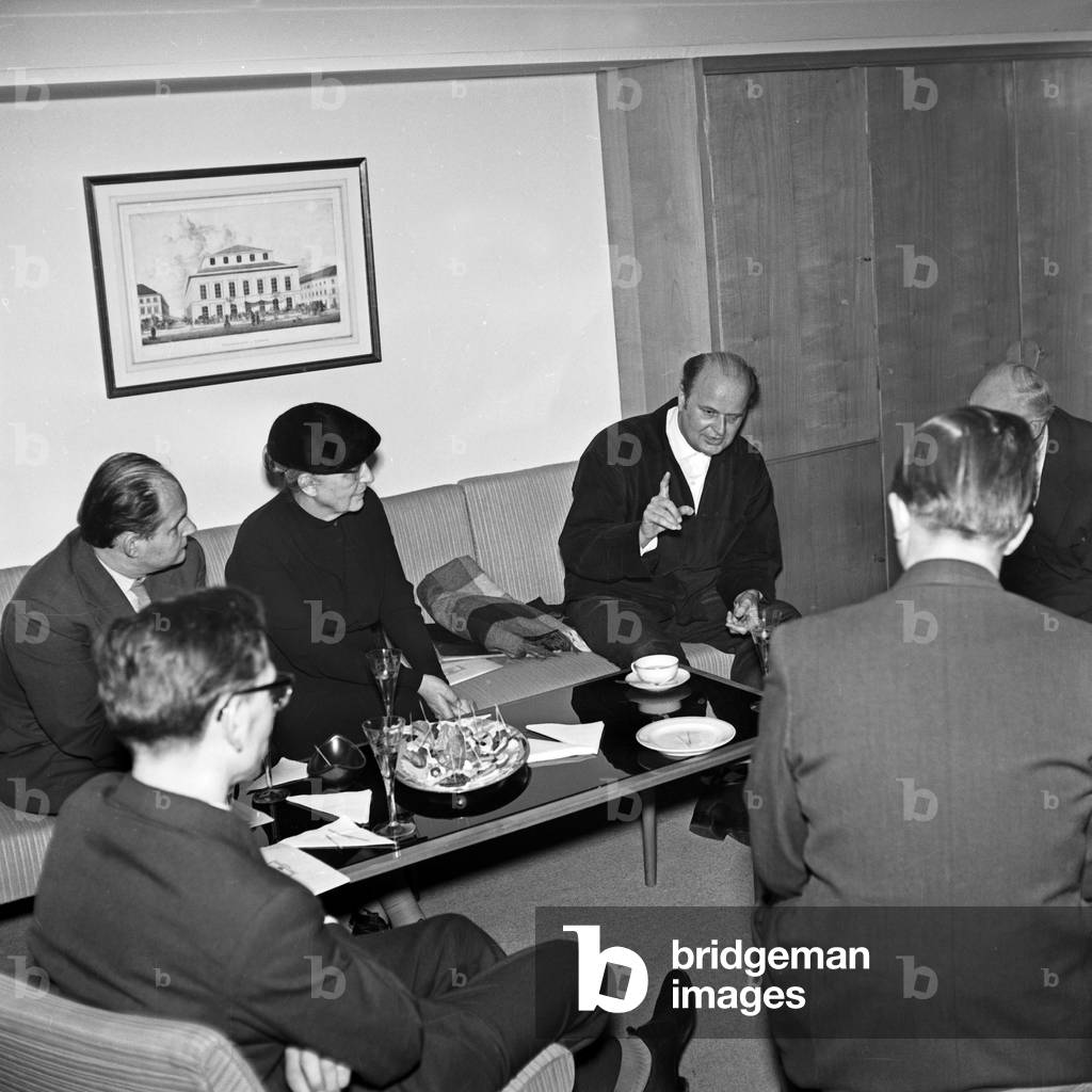 Men sitting with an elder lady at a conference room, having a glass of sparkling wine at Hamburg, Germany 1950s