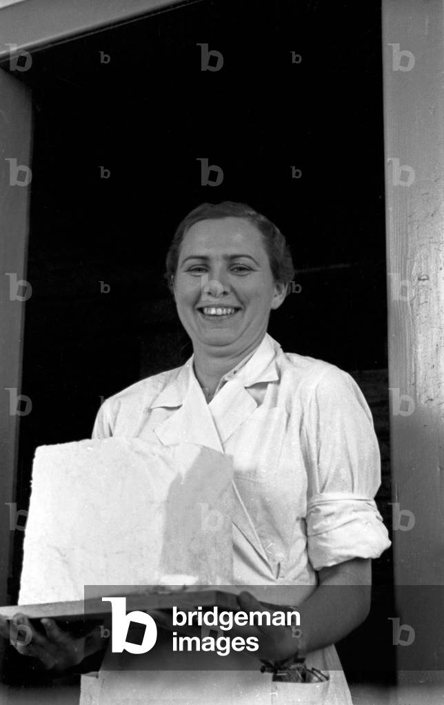 Female staff member of the Deutsche Fettsäurewerke and Maerkische Seifenindustrie company at Witten proudly presenting a block of margarine, produced from coal, Germany 1930s (b/w photo)
