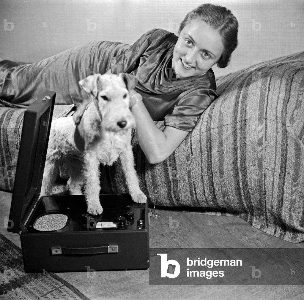 A lady and her dog pet at the photo studio in contemporary fashion, Germany 1930s (b/w photo)
