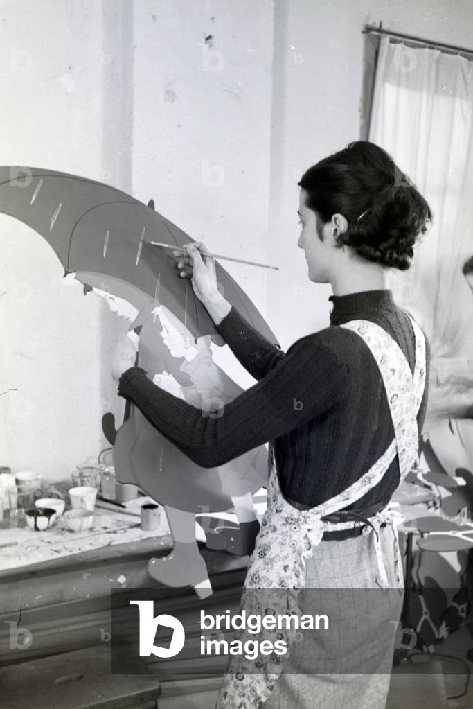 An employee of the Heller Kunst workshops in the Eifel painting a sawn out wooden figure, Germany 1930s (b/w photo)