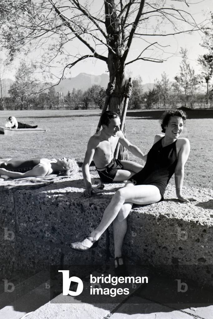 Two young women and a young man sunbathing and swimming in the Chiemsee, Dermany 1930s (b/w photo)