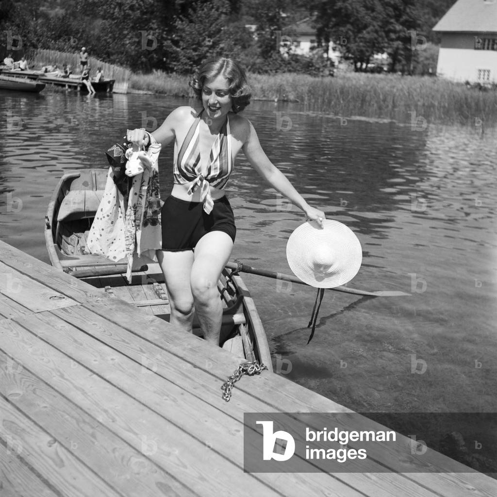 A young woman on a boardwalk on the shore of a lake in the Wachau area in Austria, Germany 1930s (b/w photo)