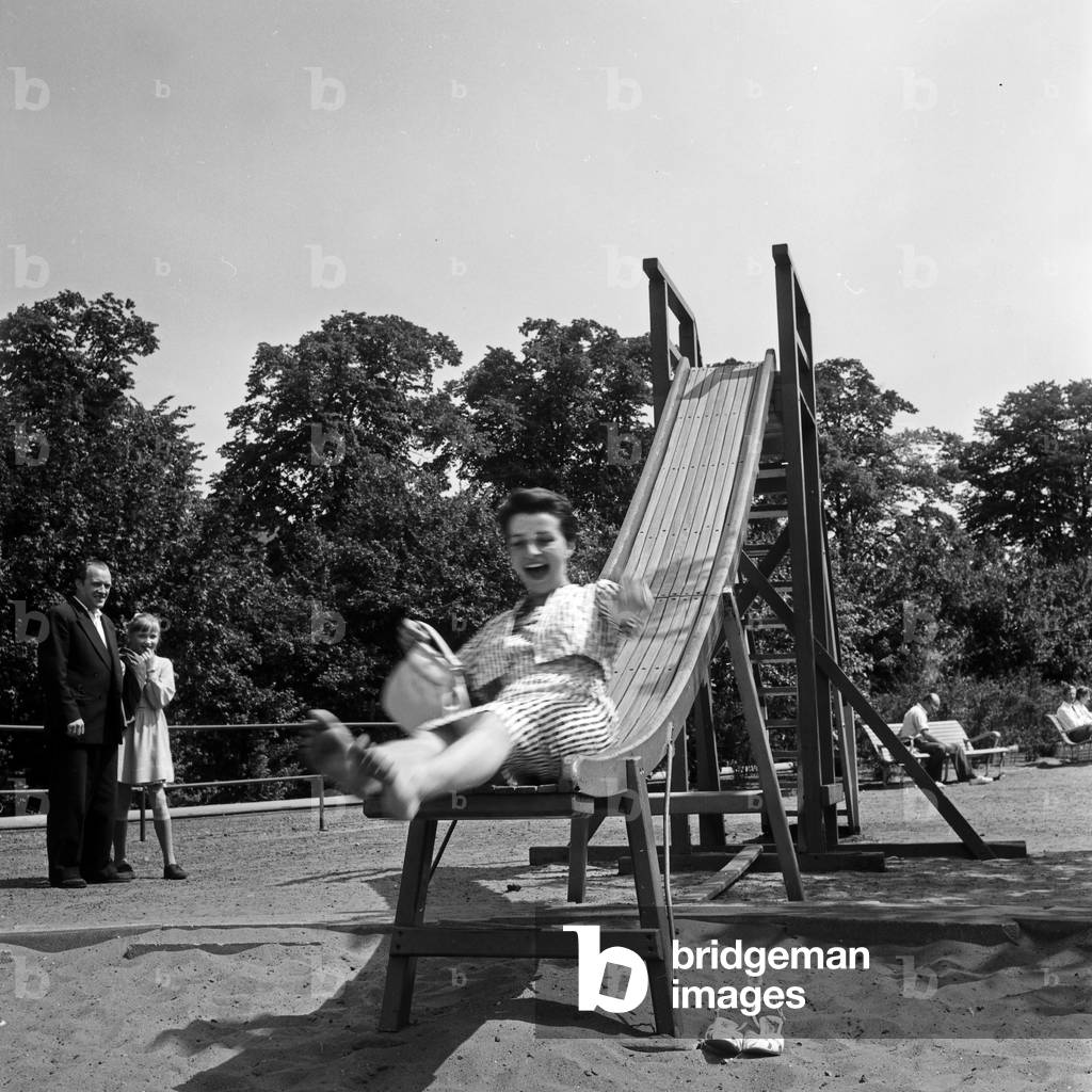 German television announcer Irene Koss on the chute of the playground at Planten un Blomen public gardens in Hamburg, Germany 1950s
